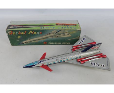 A boxed vintage tinplate friction powered #MF101 ' 'Rocket Plane'. The plane in blue, red and silver with detachable rear win
