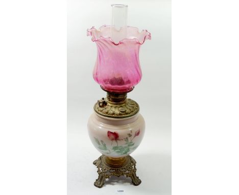 A Victorian brass mounted glass oil lamp printed roses with frilled cranberry shade 
