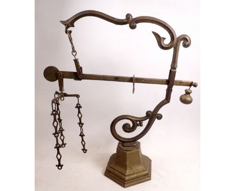A brass sack scale on scrollwork wall bracket