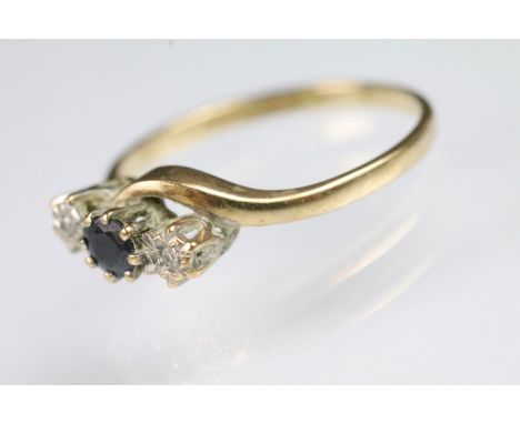 9ct gold sapphire and diamond three stone crossover ring being set with a round cut sapphire to centre flanked by two round c