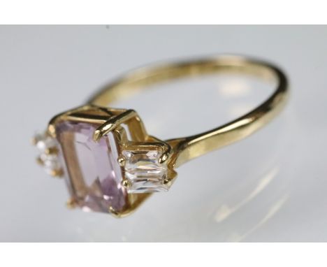 9ct gold pink synthetic sapphire and CZ ring. The ring being set with a step cut synthetic pink sapphire to centre flanked by