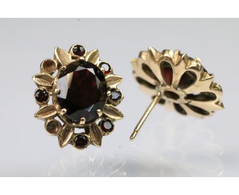Pair of vintage yellow metal and garnet stud earrings set with oval cut garnets to centre with further garnet accent stones s