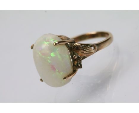 14ct gold and opal dress ring. The ring set with a opal cabochon to the head with moulded florals to the shoulders. Marked 14