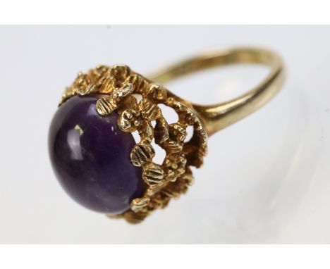 Vintage 9ct gold and amethyst ring. The ring being set with an oval amethyst cabochon set within pierced bark effect shoulder