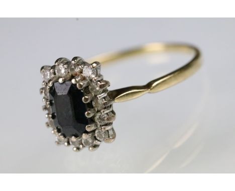18ct gold sapphire and diamond ring. The ring being set with a rectangular step cut sapphire to centre surrounded with a halo