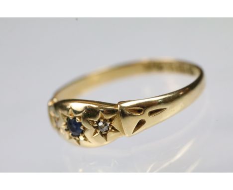 18ct gold sapphire and diamond three stone ring. The head being star set with a round cut blue sapphire flanked by two diamon