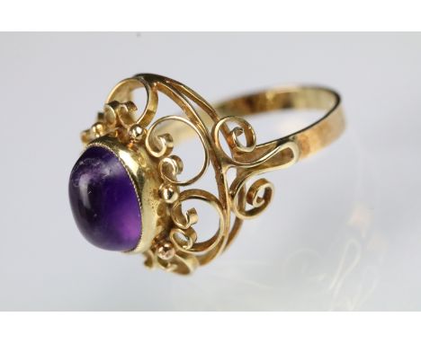 15ct gold and amethyst ring. The ring being set with an oval amethyst cabochon set within a pierced and scrolled mount. Marke