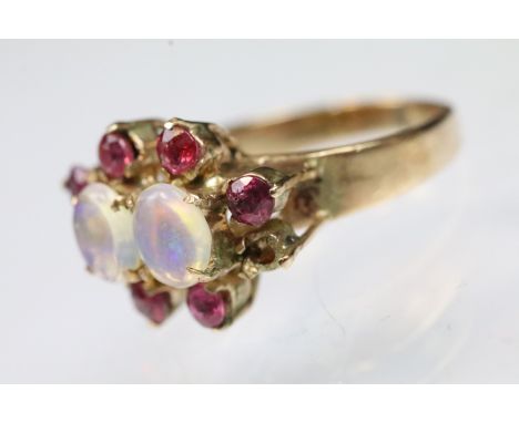 Opal and ruby cluster ring being set with two oval opal cabochons with a halo of round cut rubies. Unmarked, tests indicate 9
