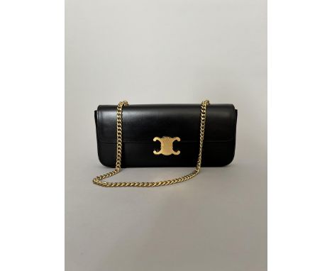 CELINE Sac Triomphe baguette en cuir noir, porté épaule. Bandoulière en métal doré. Signé. 29,5 x 14 x 4,5 cm environ. Dans s