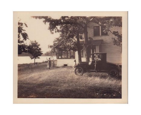 Black and white gelatine silver print photo depicting a family waving goodbye to their relative, as he gets ready to leave in