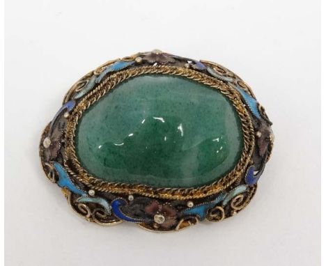 A late 20thC Oriental brooch with central jade like stone in a gilt metal mount with enamel decoration. Marked 'Silver'  1 ½”