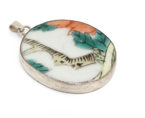 A pendant set with Oriental hand painted ceramic panel within a white metal mount. 1 ½” long CONDITION: Please Note -  we do 