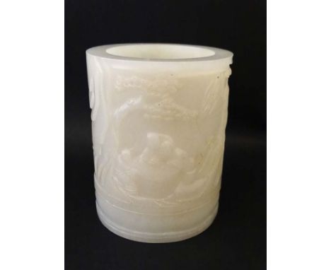 A Chinese white jade cylindrical brush pot with relief decoration of figures playing board games in a garden. 3 5/8" high  2 
