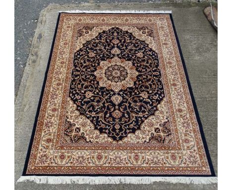 Carpet / Rug:    A machine made Persian Keshan style carpet with midnight blue / black central ground, red, buff and brown et
