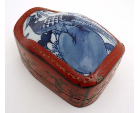 A Chinese shaped red lacquered box and cover with gilt decoration and blue and white ceramic panel with image of a pheasant t
