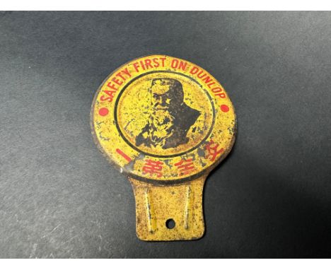 An unusual Dunlop tin 'safety first' badge with Oriental characters below an image of 'Mr Dunlop'.