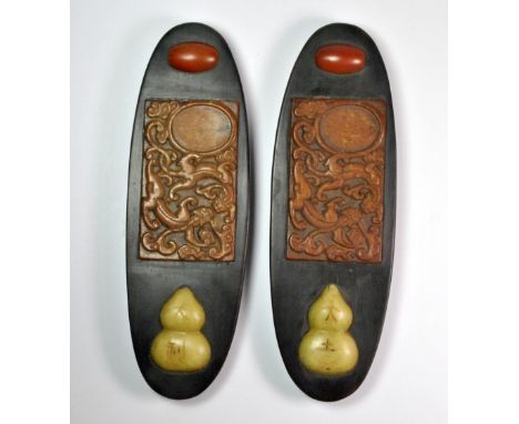 A pair of mid 20thC Chinese black hardwood scroll weights inset with carved semi-precious stones, L. 22.5cm.