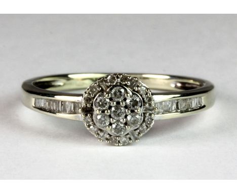 A 9ct white gold diamond cluster ring with diamond set shoulders, (P.5).