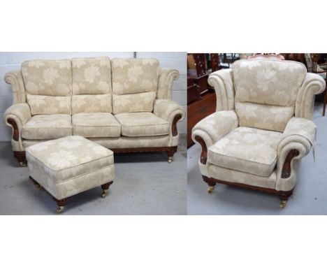 A contemporary mahogany framed beige floral upholstered three seater sofa on castors, width approx 200cm, a matching armchair