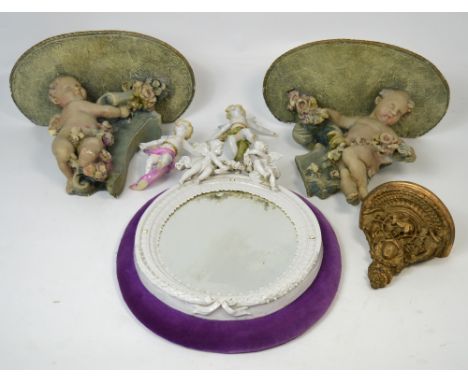 A pair of plaster cherubic wall mounts, a smaller gilt heightened wall mount, a white glazed ceramic wall mirror with cherub 