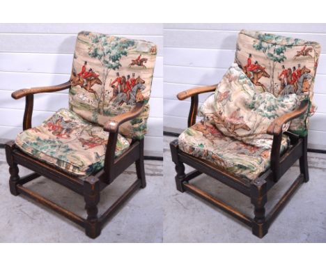 A pair of oak armchairs upholstered in hunting scene linen fabric.
