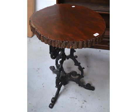 An occasional table with naturalistic wooden top on black cast iron tripod support, height 75cm.