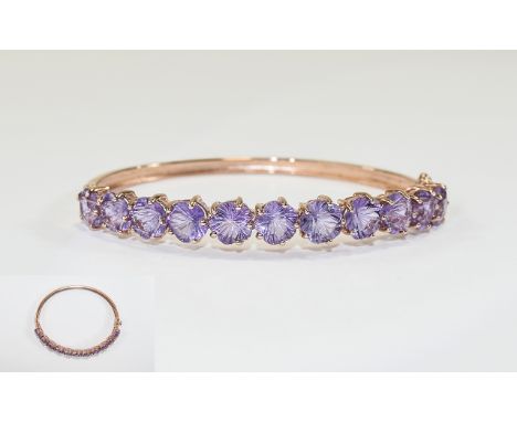 Rose de France Amethyst Bangle, a row of eleven flower cut amethysts totalling 15cts, set on an oval, hinged bangle of rose g