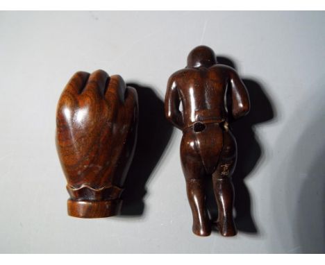 Netsuke - two vintage dark wood Japanese netsukes one in a form of a hand, holding a small monkey, the other is erotic style 