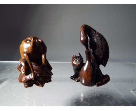 Netsuke - two vintage dark wood Japanese netsukes one in a form of a large bird, holding his beak in a bottle and a small dog