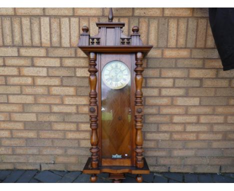 A walnut cased Vienna style wall clock with turned decoration, two piece celluloid dial, seconds indication, with weights, wi