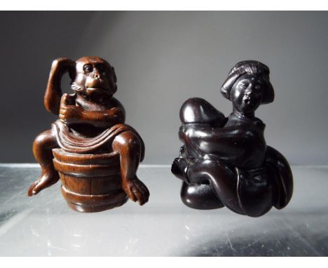 Netsuke - two vintage dark wood Japanese netsukes one in a form of a monkey sitting on a barrel, the other is erotic style de