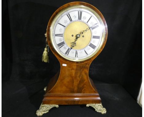 A large and unusual balloon shaped mantel clock, flame mahogany with inlaid stringing, lions head handles and supported on ca