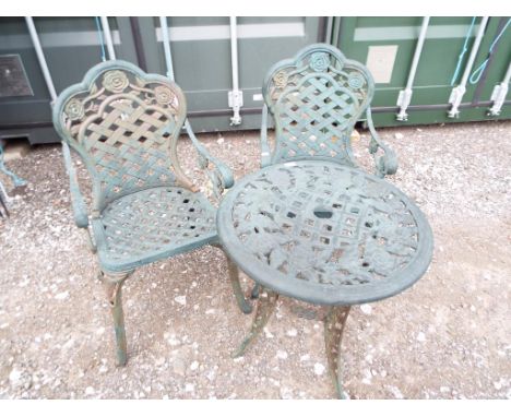 A cast iron garden patio set comprising a table and two armchairs, table approx height 67cm (h) x 60cm (diam) marked to base 
