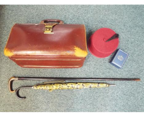 A lot to include a vintage leather bag, ebonised walking cane with silver collar (hallmarks unclear) a fez and a boxed Halcyo