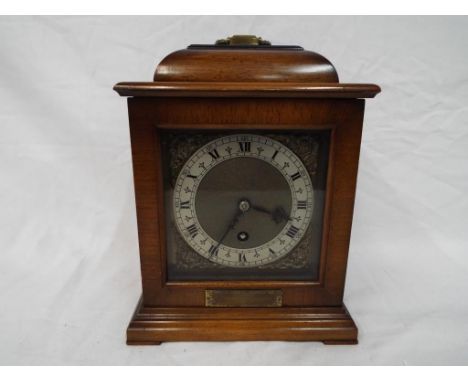 A mahogany cased mantel clock, the dial with Roman numerals to a silver chapter ring with applied corner spandrels, ca 1940s,