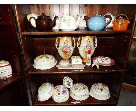 Three shelves containing a quantity of ceramics to include teapots, jelly moulds, a pair of European vases, a trinket dish wi