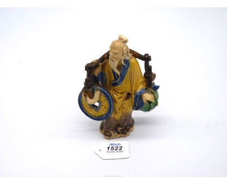 A fine vintage Chinese 'shiwan' pottery figure of an ancient bearing a yoke from which hang emblems of good luck including a 