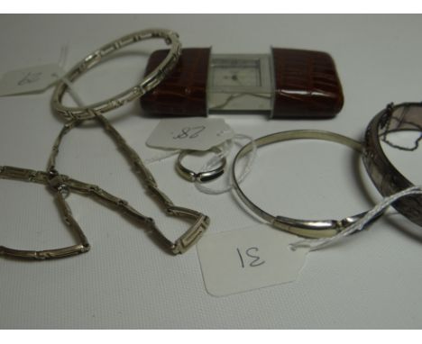A modern pseudo-crocodile skin slide-to-view travel-clock; together with a bright-cut floral silver clasp bangle, a silver ba