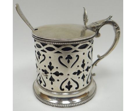 A Victorian pierce-work silver mustard pot with Bristol-blue glass liner and having scrolled handle with thumb-piece to the h