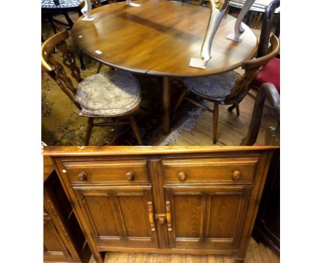 An Ercol medium elm dining suite comprising drop leaf dining table, four chairs and sideboard having two drawers above two pa