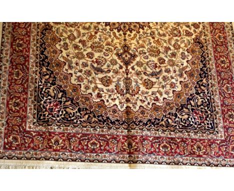 A Keshan carpet on a cream ground with red border and floral motifs.