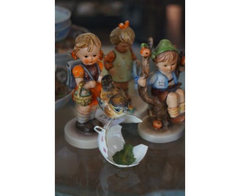 A collection of three Goebel figurines together with a modern Worcester model of a bird perching on a broken tea cup.