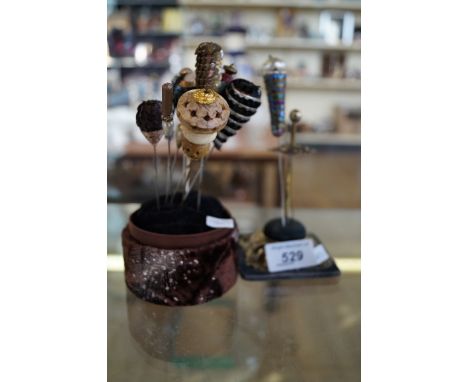 Two hat pin cushions with twelve hat pins to include mother of pearl examples.