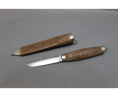 A Finnish Puukko hunting knife, with a 3 1/2" blade, marked Christiana with carved wooden handle and matching carved scabbard