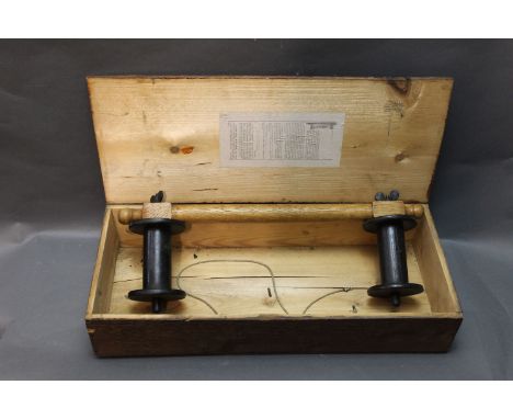 A vintage line drier, having an oak shaft and black painted rollers, housed within a pine box with instructions to the lid, w