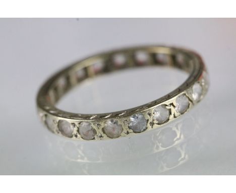 Vintage white stone eternity ring set throughout with round cut white stones set within a yellow metal mount. Surface tests i