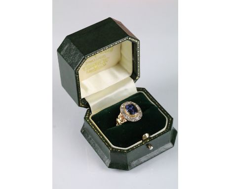 Antique sapphire and diamond cluster ring. The ring being bezel set with an oval mixed cut blue sapphire with a halo of old c
