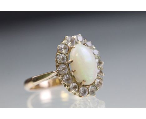 Opal and white sapphire halo ring. The ring being set with an oval opal cabochon with a halo of round brilliant cut white sap