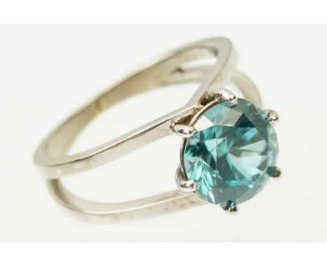 18ct white gold and zircon dress ring. The ring being set with a round brilliant cut blue zircon prong set to a split shoulde