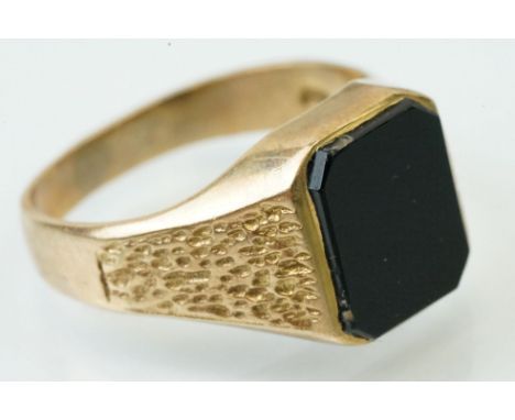 9ct gold signet ring set with a black stone panel to the head with textured shoulders. Hallmarked London 1973. Size U. 